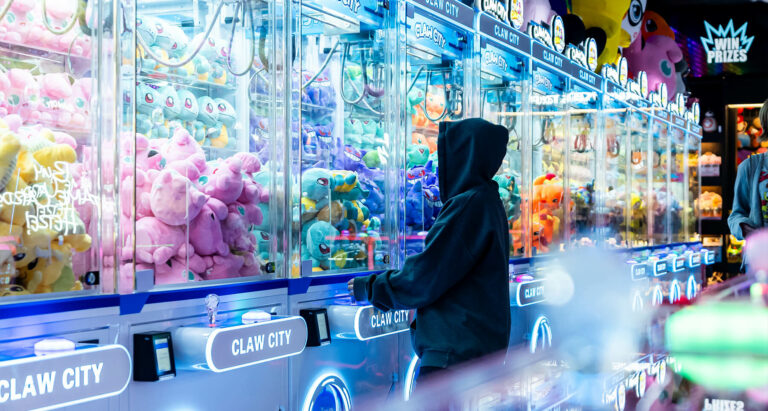 A kid with a black hoodie playing a Squirtle Pokemon claw machine